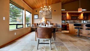 A dining area with a wooden ceiling, a chandelier, and a view of the outdoors through large windows. - Coastal Luxury: Chef Kitchen, Ocean Views, Hot Tub (Sea Ranch)