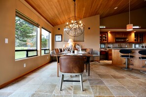A dining area with a wooden ceiling, a chandelier, and a view of the outdoors through large windows. - Coastal Luxury: Chef Kitchen, Ocean Views, Hot Tub (Sea Ranch)