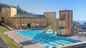 Ein hölzernes Gebäude mit Schwimmbecken, Stufen, die zum Pool führen, und Blick auf den Ozean.