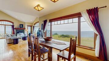 A spacious dining area with a wooden table and chairs, a large window with a view, and a cozy seating area with a sofa and a fireplace.