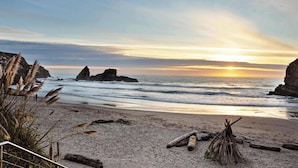 Une plage avec des formations rocheuses, un coucher de soleil et un ciel dégagé.