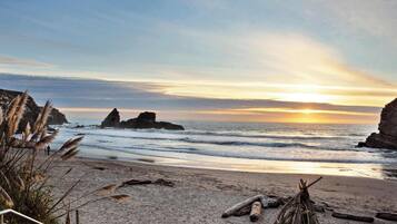 A beach with rocky formations, a sunset, and a clear sky.