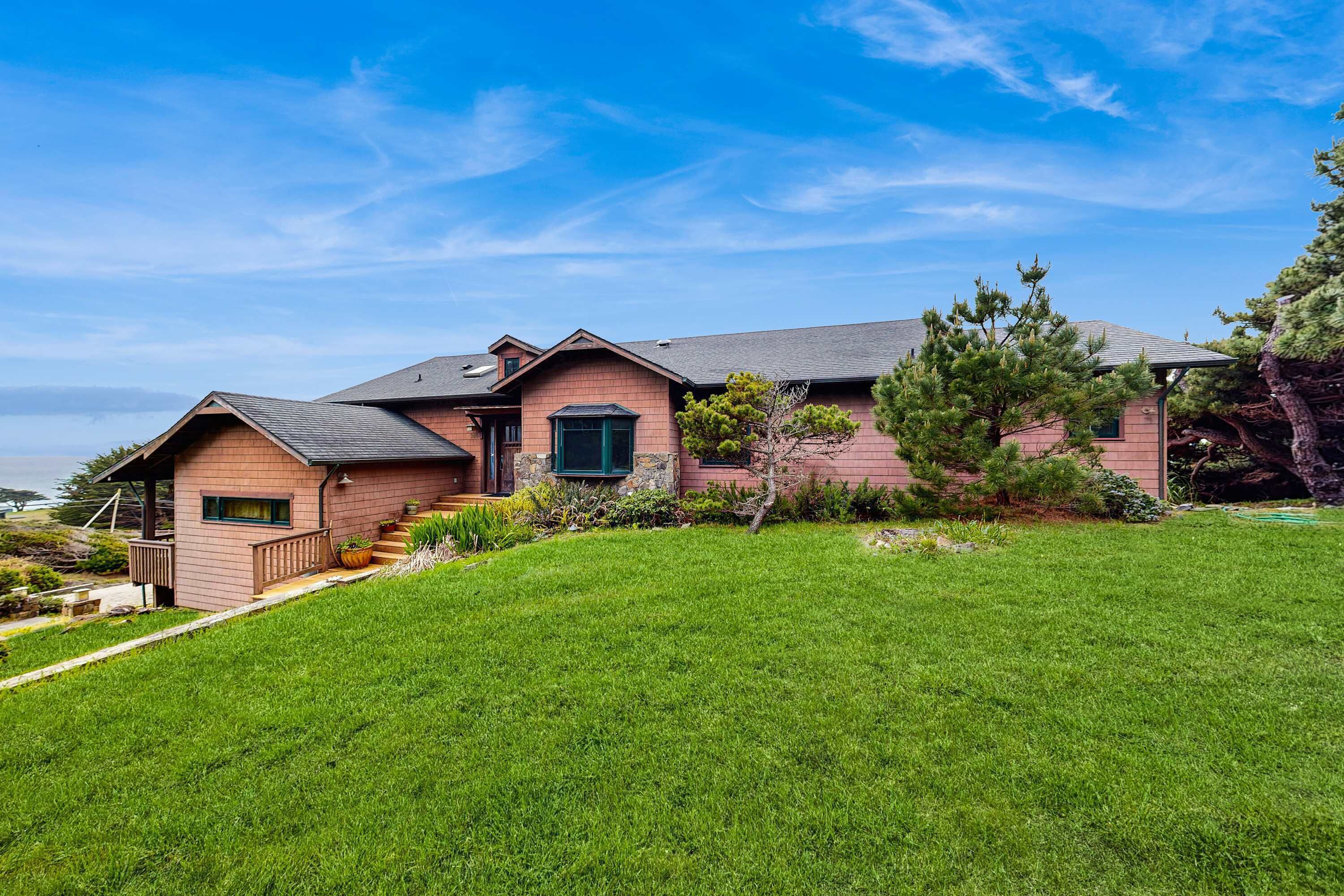 A two-story house with a sloped roof, a front porch, and a well-maintained lawn.