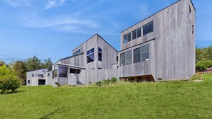 A modern two-story house with a sloped roof, large windows, and a flat roof extension. - Sea Ranch 2BR ocean-view home with private hot tub & courtyard (Sea Ranch)
