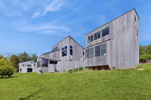 A modern two-story house with a sloped roof, large windows, and a flat roof extension. - Sea Ranch 2BR ocean-view home with private hot tub & courtyard (Sea Ranch)