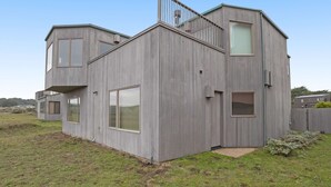 Una casa moderna con techo plano, ventanas amplias y una escalera visible.