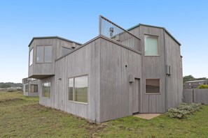 Ein modernes Haus mit Flachdach, großen Fenstern und einer sichtbaren Treppe.