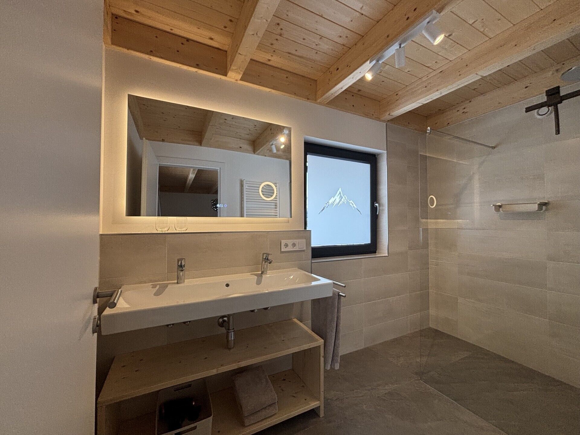 Een moderne badkamer met een houten plafond, een grote spiegel, een wastafel en een douche.