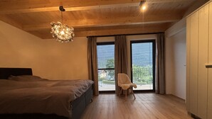 A bedroom with a large bed, a chair, and a view through the window. - New luxury villa—for outdoor adventures in both summer and winter! (Gundersheim)
