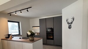 A modern kitchen with a central island, built-in appliances, and a decorative deer head on the wall. - New luxury villa—for outdoor adventures in both summer and winter! (Gundersheim)