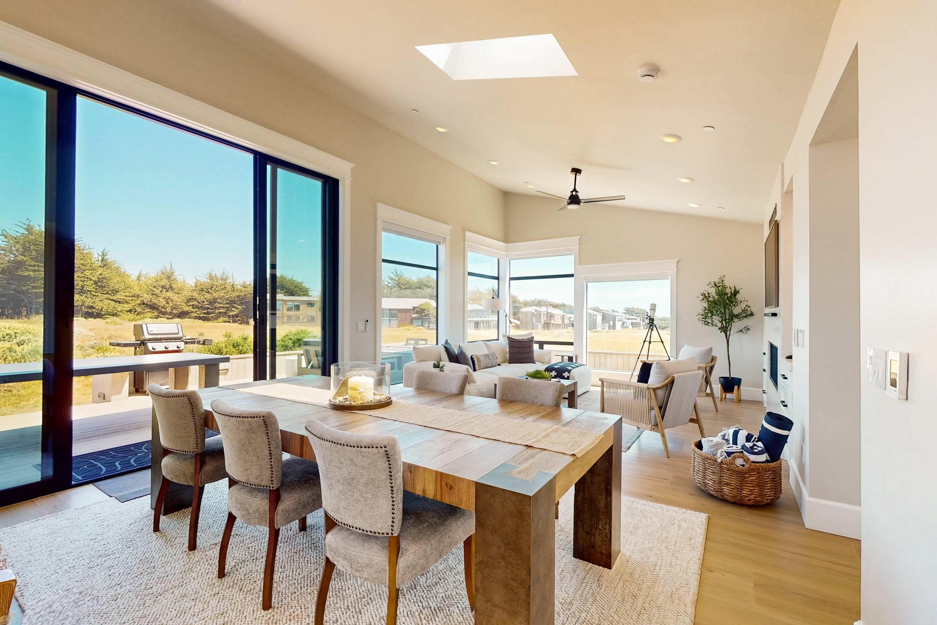 A modern dining area with a large table, chairs, and a view of the outdoors.