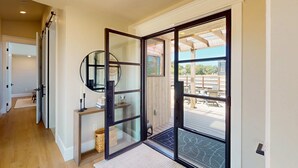 A modern interior with a sliding glass door leading to an outdoor patio area. - Luxe newly built Sea Ranch home with private hot tub & ocean views (Sea Ranch)