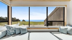 Ein modernes Zimmer mit großem Fenster, einer eingebauten Bank mit Kissen und Meerblick.