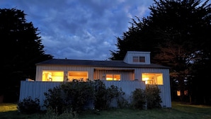 A single-story house with a sloped roof, a small attached garage, and a fenced yard. - Sea Ranch 2BR ocean-view home with private hot tub & fireplace (Sea Ranch)