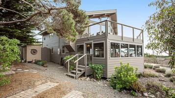 A two-story house with a balcony, a staircase, and a gravel driveway.
