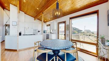A modern kitchen with white cabinets, a central island, and a dining area with a round table and chairs.