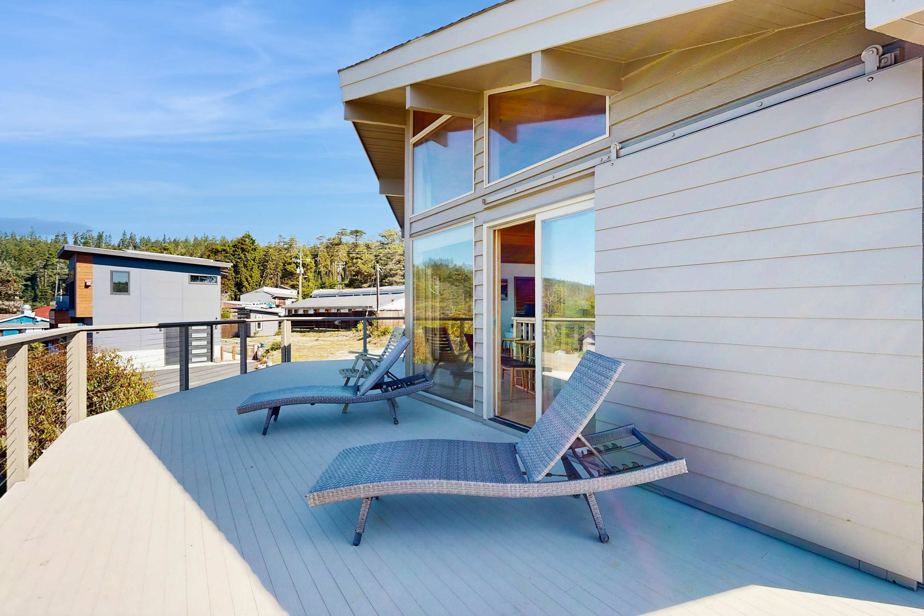 A modern building with a balcony featuring two lounge chairs and a glass door leading to an interior space.