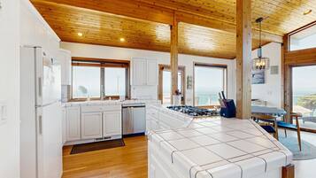A modern kitchen with white cabinets, a large island, and wooden ceiling beams.