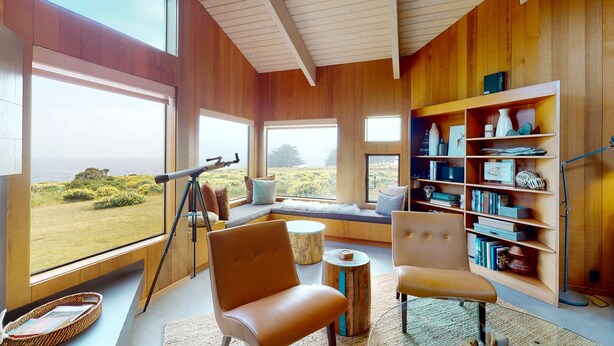 A room with large windows, a telescope, a bookshelf, and a seating area. - Sea Ranch 3BR oceanfront home near Shell Beach & Bluff Trail (Sea Ranch)