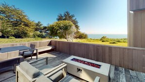 An outdoor deck with a fire feature, seating, and a view of the ocean. - Sea Ranch 3BR oceanfront home near Shell Beach & Bluff Trail (Sea Ranch)