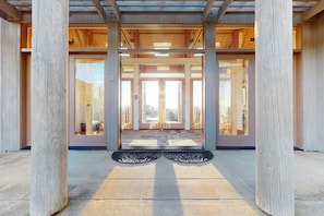 A building entrance with a wooden structure, large glass doors, and a tiled floor. - Sea Ranch 3BR hot tub — Meadow home with hot tub & trail ac (Sea Ranch)