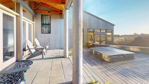 Un edificio moderno con amplios ventanales, una terraza de madera y asientos al aire libre.