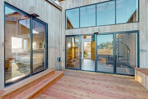A modern building with large glass doors and a wooden deck. - Ocean-view meadow home with private hot tub, dogs welcome (Sea Ranch)