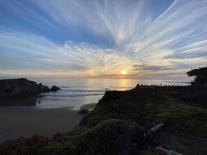 A coastal sunset with a calm sea, rocky outcrops, and a wooden fence. - Updated coastal home with tranquil ocean views, gas grill, private deck (Gualala)