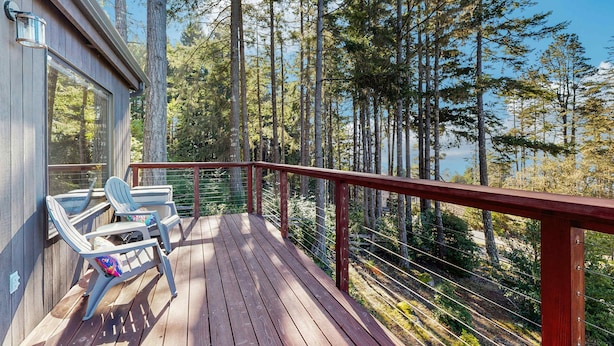 A wooden deck with chairs and a railing overlooking a forested area. - Gualala 3BR updated coastal home with ocean views & private deck (Gualala)