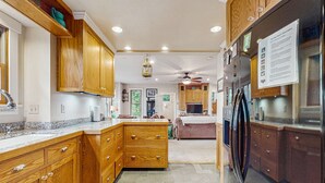 A kitchen with wooden cabinets, a refrigerator, and a ceiling fan. - Sea Ranch 2BR forested home on the hillside — dog friendly (Sea Ranch)