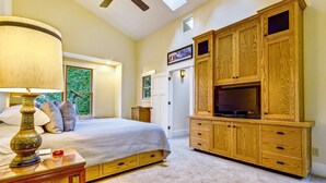 A bedroom with a bed, a TV cabinet, a lamp, and a window. - Sea Ranch 2BR forested home on the hillside — dog friendly (Sea Ranch)