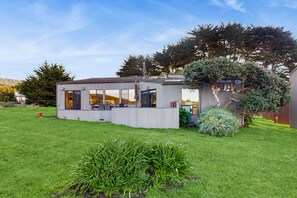 A modern house with a patio, a large tree, and a well-maintained lawn. - Sea Ranch 2BR ocean-view home with hot tub near Shell Beach (Sea Ranch)