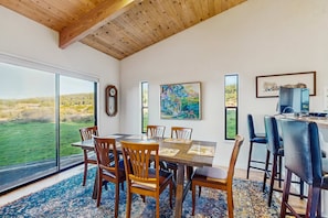A dining area with a large table, chairs, and a view of the outdoors. - Sea Ranch 2BR ocean-view home with hot tub near Shell Beach (Sea Ranch)