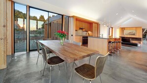 Een moderne keuken met een houten tafel en stoelen, een eethoek met een groot raam en uitzicht op de omgeving.
