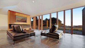 Een moderne woonkamer met een groot raam, een bank, twee fauteuils en een salontafel.