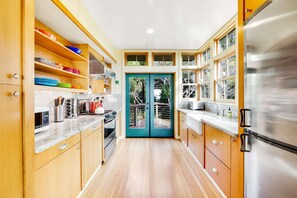 A kitchen with wooden cabinets, a stainless steel refrigerator, and a double door leading to an outdoor area. - Gualala 2BR ocean views — Gualala craftsman home with ocean v (Gualala)