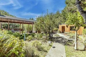 Eine Holzhütte mit überdachter Terrasse und einem Gartenweg, der dorthin führt.