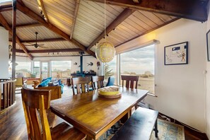 A dining area with wooden furniture, a globe light fixture, and a view of the outdoors. - Newly remodeled hexagon home with hot tub, dogs welcome (Sea Ranch)