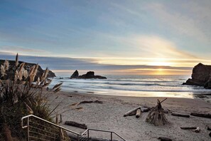 A beach with a sunset, rocky formations, and a metal staircase leading down to the shore. - Gualala 2BR oceanfront blufftop home with hot tub — sleeps 4 (Gualala)