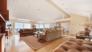 A spacious living area with a high ceiling, large windows, and a view of the ocean. - Gualala 2BR oceanfront blufftop home with hot tub — sleeps 4 (Gualala)