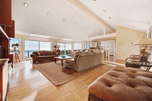 A spacious living area with a high ceiling, large windows, and a view of the ocean. - Gualala 2BR oceanfront blufftop home with hot tub — sleeps 4 (Gualala)