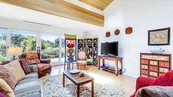 A living room with a sofa, armchair, coffee table, and a television.