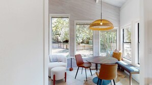 Een eetgedeelte met een ronde tafel, stoelen, een bank en een hanglamp.
