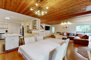 A modern interior with a wooden ceiling, a central bed, a sofa, a dining area, and a kitchen. - Sea Ranch home with deck & grill near Shell Beach, dogs welcome (Sea Ranch)
