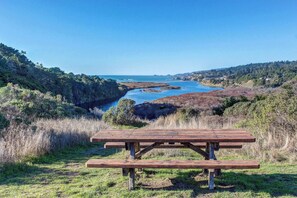 A picnic table in a natural setting with a view of a body of water and hills. - Sea Ranch 2BR dog-friendly home with hot tub & golf-course views (Sea Ranch)