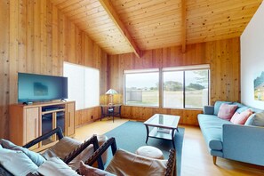 A wooden-paneled room with a television, sofa, and a table. - Sea Ranch 2BR dog-friendly home with hot tub & golf-course views (Sea Ranch)