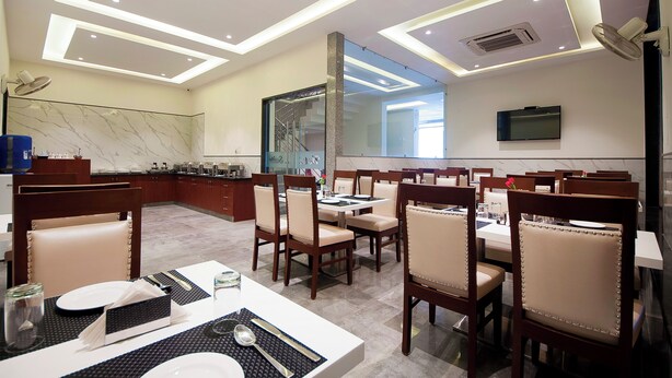 A modern dining area with wooden chairs and tables, a large mirror, and a TV on the wall. - Z Premium Suites -Near IGI Delhi Airport (New Delhi)
