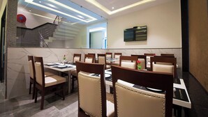 A modern dining area with marble walls, a staircase, and a flat-screen TV. - Z Premium Suites -Near IGI Delhi Airport (New Delhi)