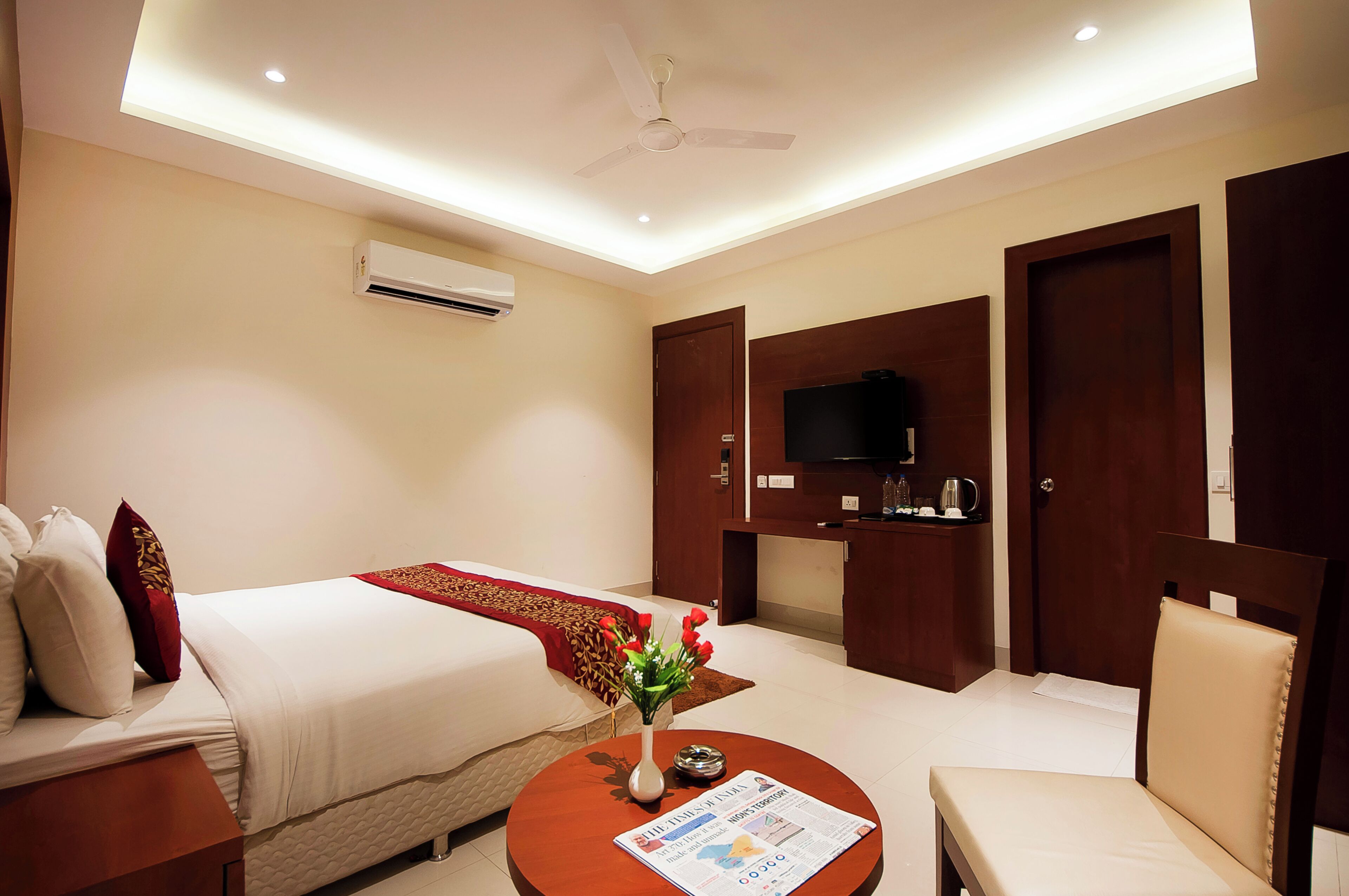 Una habitación de hotel con cama, televisión, cafetera y escritorio con silla.