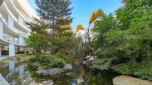 Um edifício moderno com um pátio que apresenta um lago, pedras e vegetação.